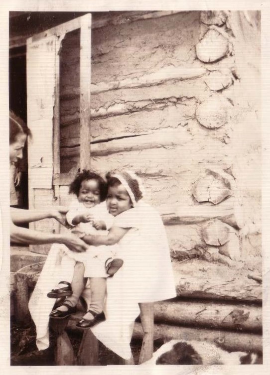 From left to right – Shirley’s mother Velma with outstretched arms to Shirley sitting on older sister Carene’s lap – in front of their home in Amber Valley, 1934 From left to right – Shirley’s mother Velma with outstretched arms to Shirley sitting on older sister Carene’s lap – in front of their home in Amber Valley, 1934